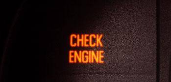 A "CHECK ENGINE" warning light illuminated in orange on a vehicle dashboard.