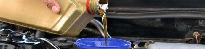 Motor oil being poured from a container into a vehicle engine.