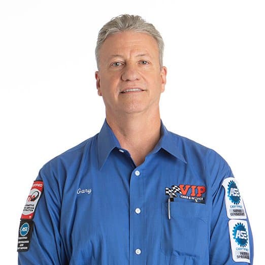 Middle-aged man with gray hair wearing a blue work shirt with racing patches and logos.