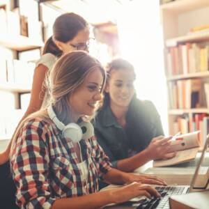 college students researching with computers and books in the library