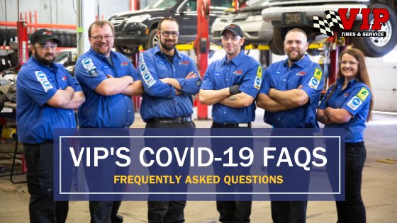 Team of mechanics in blue uniforms stand in a garage with a sign reading "VIP's COVID-19 FAQS.