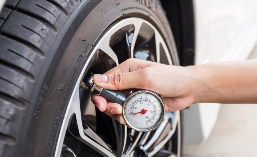 A person holding a gauge on a tire, checking its pressure.