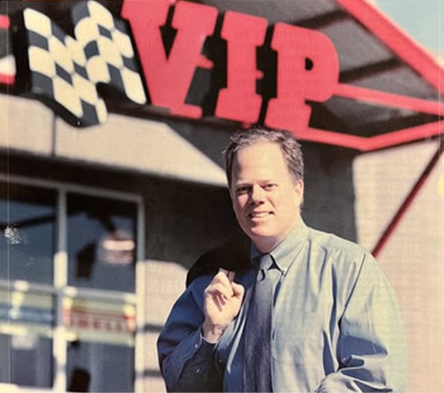 Man in blue shirt standing in front of a VIP sign.
