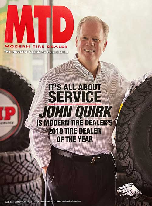 Man wearing MTD magazine cover shirt standing in front of tire display.