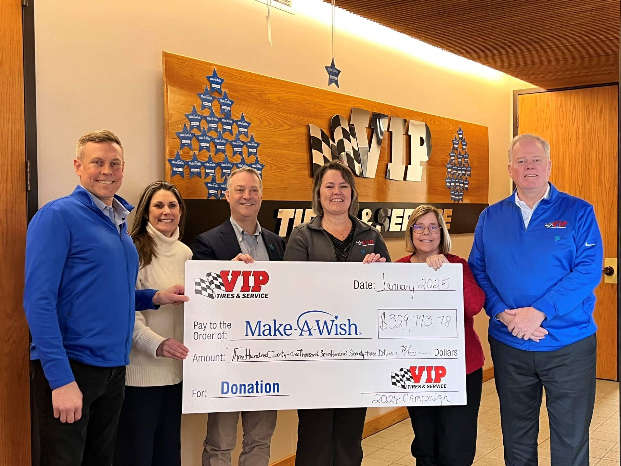 Six people hold a large VIP Tires & Service donation check to Make-A-Wish Foundation.