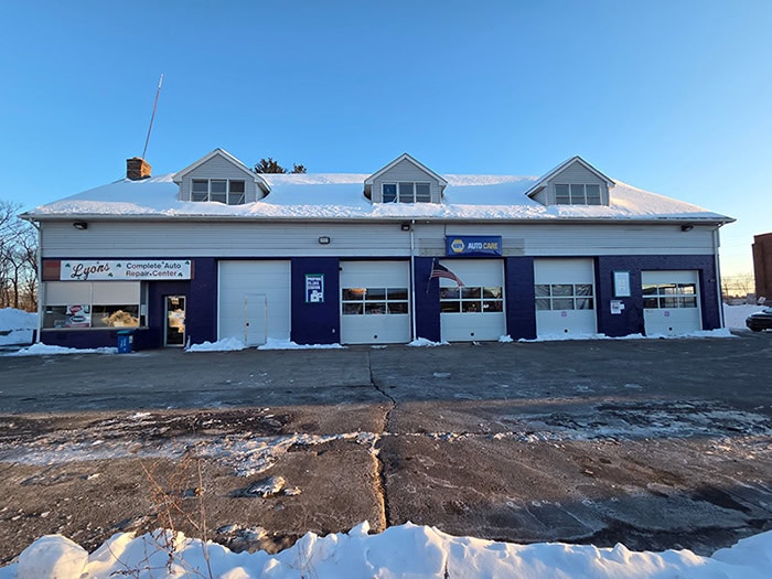 A single-story commercial building with three peaked roof sections and blue trim sits behind.