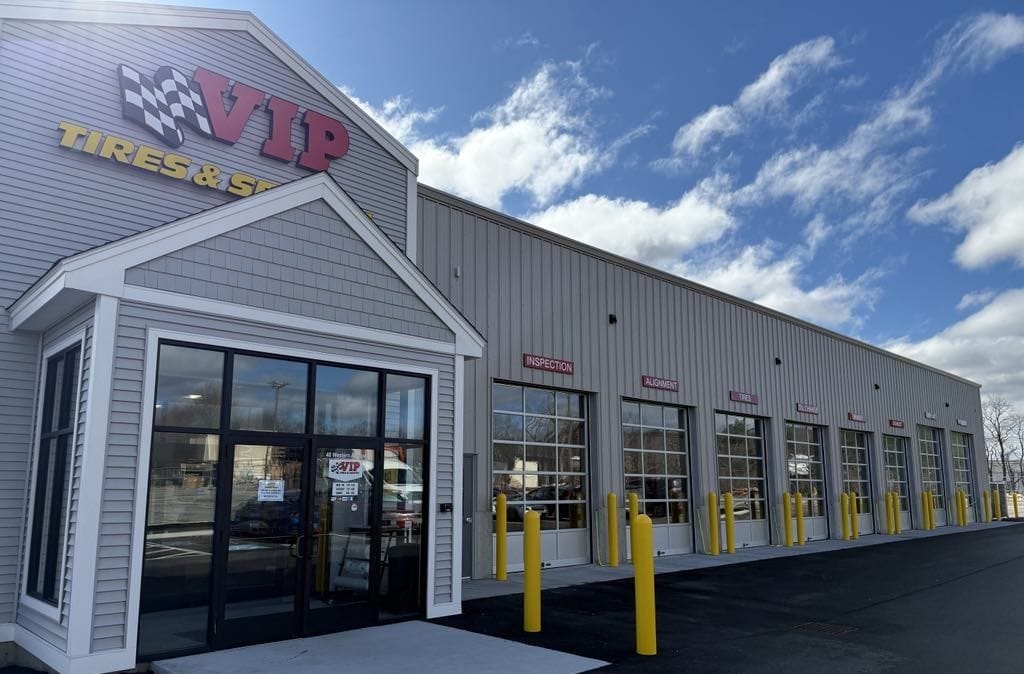VIP Tires & Services automotive shop exterior with multiple service bays and yellow safety bollards.