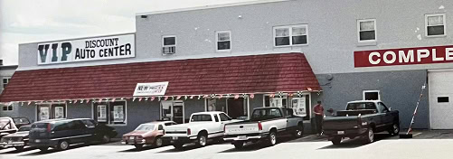 Exterior of a red and gray auto parts building with parked vehicles in front.