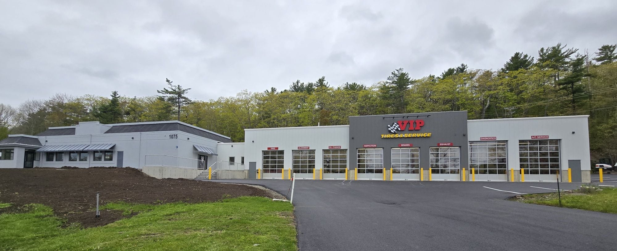 Modern automotive service facility with multiple garage bays and adjacent office building.