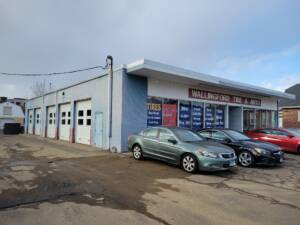 Wallingford Tire & Auto shop with three cars parked in front on an asphalt lot.