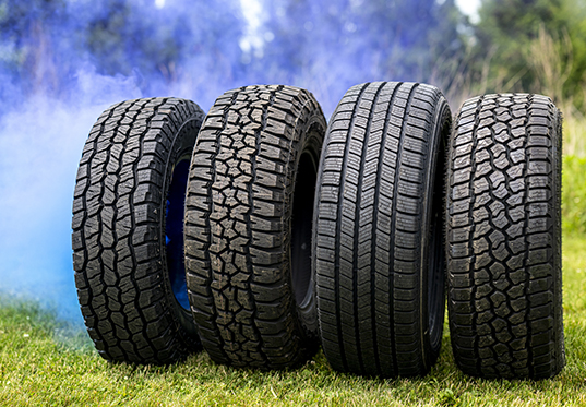 4 different types of Vredestein tires on grass with a blue smoke drifting up behind it