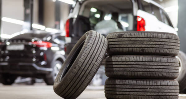 Used tires sitting in front of two cars in the shop.