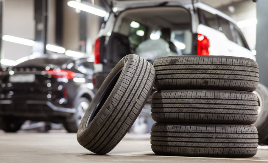 Used tires sitting in front of two cars in the shop.